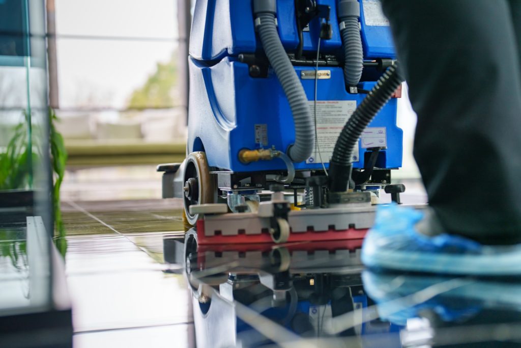 Worker cleaning office lobby floor with machine